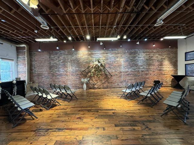 The Ballroom set for a ceremony: rows of chairs on the hardwood floor facing a diamond arch on the brick wall.