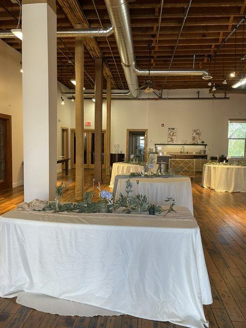 The Ballroom looking toward the front windows, with wood columns, beam ceiling and a long draped table.