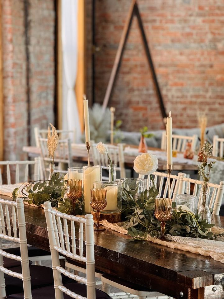 Taper candles, amber glass and a greenery runner on a wooden farm table in the Loft.