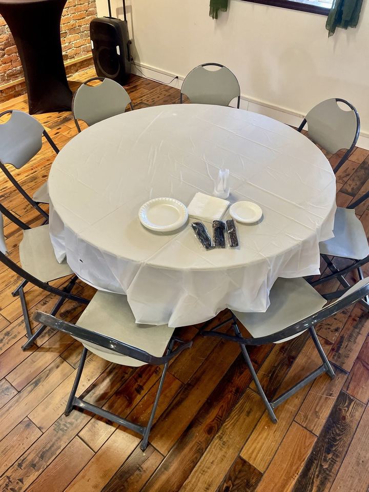 The Rent A Room set-up: a round table in a plastic cloth with paper plates, plastic cutlery and folding chairs.