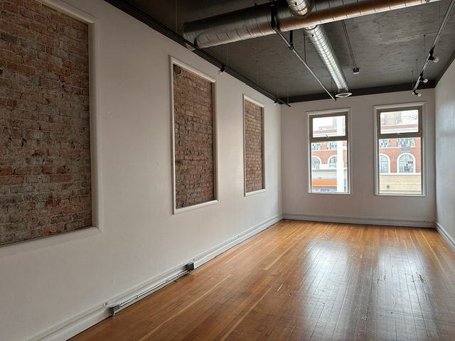 A white-walled room in the Suite with exposed-brick panels and two windows.