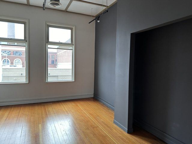 A grey room in the Suite with two windows.